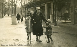 Paula Naumann mit ihren beiden Kindern Marga und Elfried vor dem Geschäft, 1929. Auf dem Schild im Bildhintergrund wird "R. Naumann" als Geschäftsführer genannt. (Foto Stadt- und Kreisarchiv Paderborn/ Familie Karkos) 